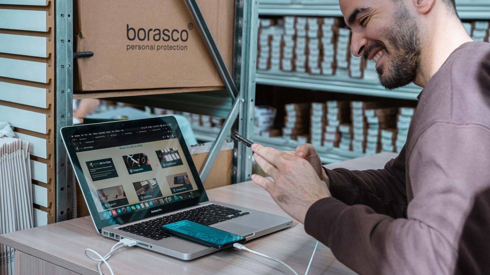 A business owner running an online storefront on a laptop in their stockroom.
