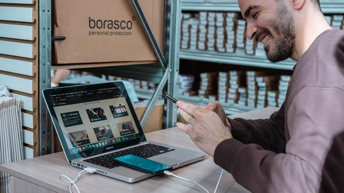 A business owner running an online storefront on a laptop in their stockroom.